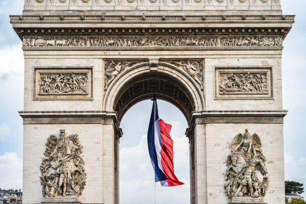 Paris, France : large French flag flying under the Arc de Triomphe for commemoration days (world wars, Bastille day).