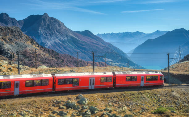 istock Red modern train is winding through the swiss alps on a sunny autumn day. Landscape with moving train, alpine mountain valley, orange hills, blue sky at sunset in fall. Bernina Express, Switzerland 2185496830