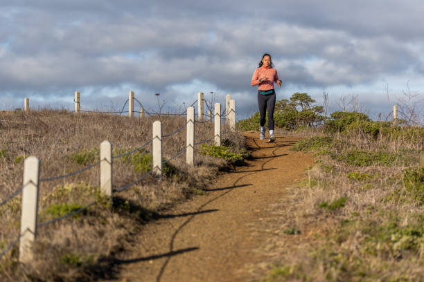 Stock photo of an Asian American trail runner in foothills near the California coast.