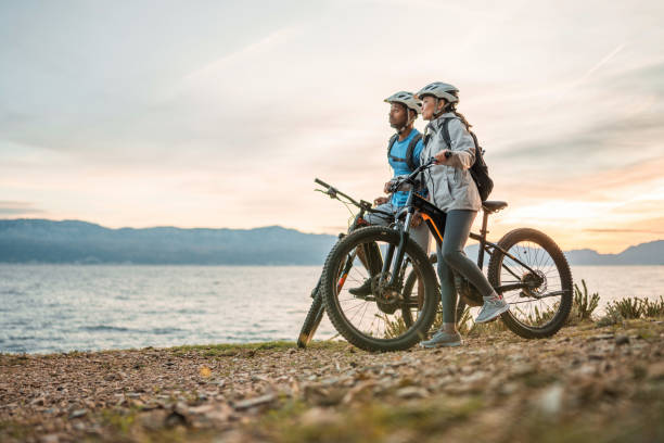 Seaside Adventure at Sunrise with Diverse Couple and E-Bikes