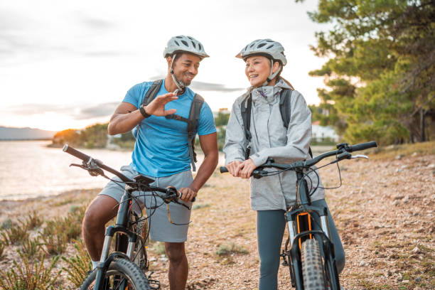 Diverse Couple with E-Bikes Relishing Seaside Dawn