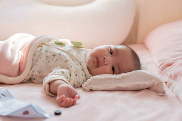 The baby is lying in bed looking at the camera