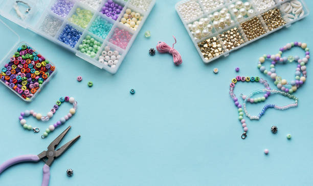istock Colorful assortment of beads and jewelry-making tools on a blue surface with completed bracelets 2185508024