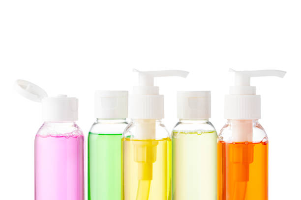 Various bottles with colored liquids and pumps arranged on white background for beauty