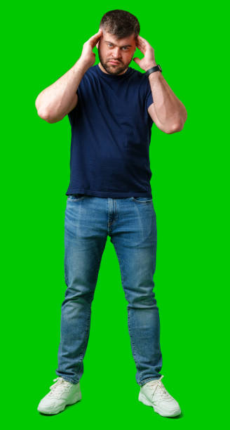 istock A man with closed eyes holds his head in a thoughtful pose against a bright green backdrop 2185508613