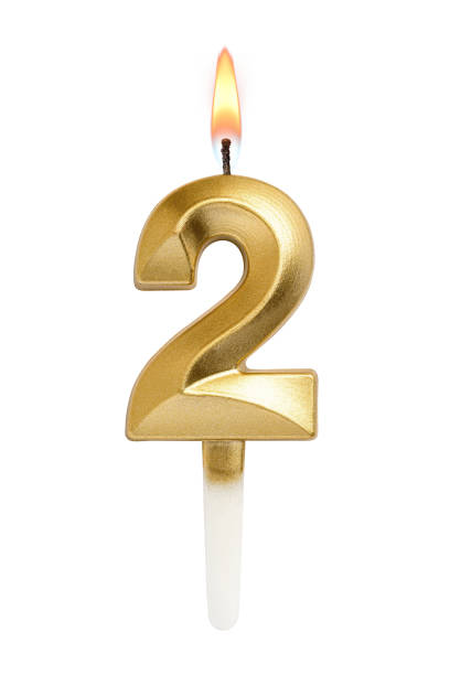 istock Golden decorated burning birthday candle digit two shaped isolated on white. 2185508718