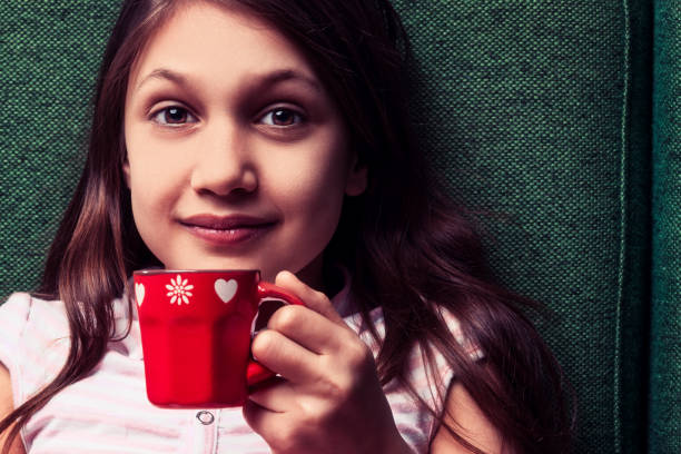 istock Smiling girl relaxing on sofa with red mug 2185512046