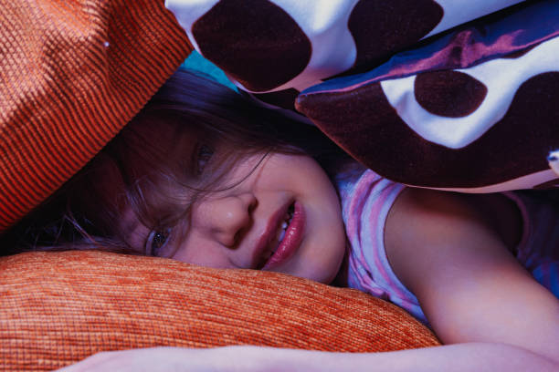 Young child peacefully sleeps among orange pillows, evoking sweet dreams