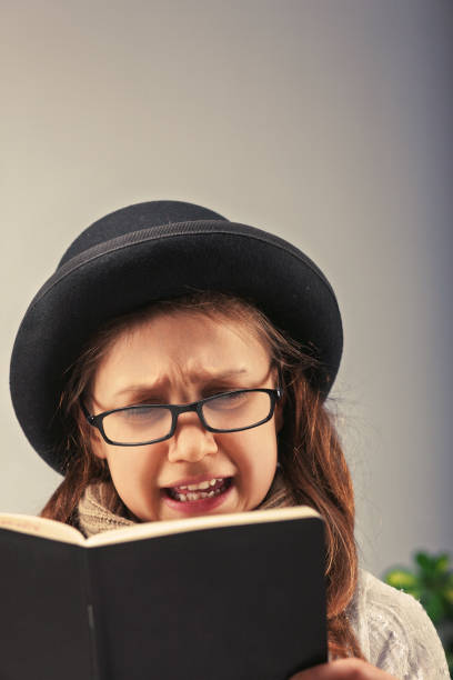 istock Little girl reading a book and making a funny face 2185512456