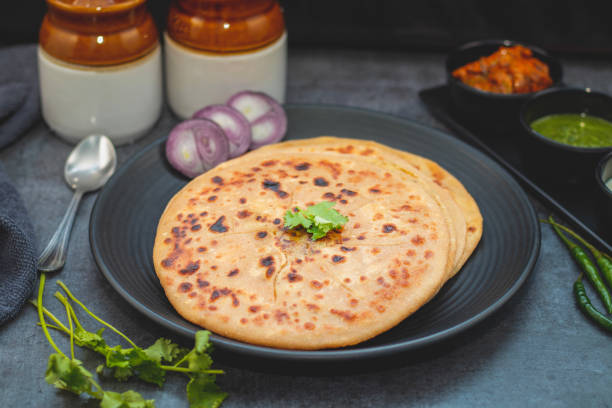 istock Aloo paratha, a golden-brown Indian flatbread stuffed with spiced mashed potatoes, is served with tangy achar (pickle) and refreshing chutney, creating a perfect blend of flavors for a comforting, savory delight. 2185512829