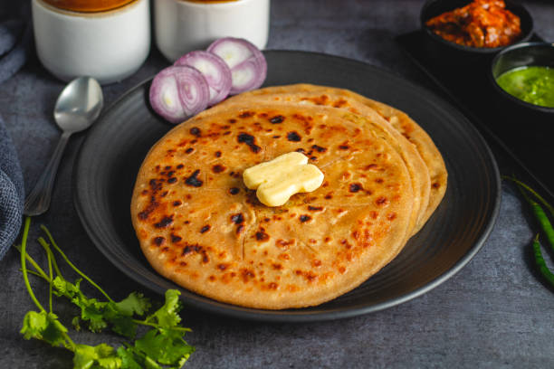 istock Aloo paratha, a flavorful Indian flatbread stuffed with spiced mashed potatoes, served hot with tangy pickle (achar) and refreshing chutney, creating a perfect balance of zest and warmth. 2185512844