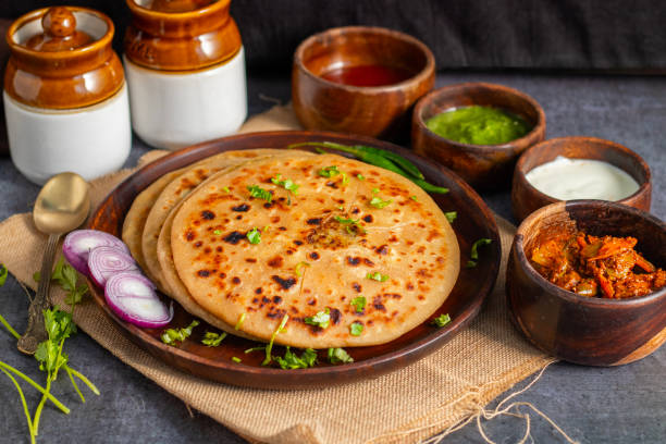 istock Aloo paratha, a golden-brown Indian flatbread stuffed with spiced mashed potatoes, is served with tangy achar (pickle) and refreshing chutney, creating a perfect blend of flavors for a comforting, savory delight. 2185512883