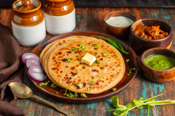 istock Aloo paratha, a flavorful Indian flatbread stuffed with spiced mashed potatoes, served hot with tangy pickle (achar) and refreshing chutney, creating a perfect balance of zest and warmth. 2185512918