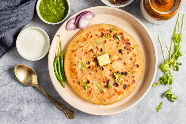 istock Aloo paratha, a golden-brown Indian flatbread stuffed with spiced mashed potatoes, is served with tangy achar (pickle) and refreshing chutney, creating a perfect blend of flavors for a comforting, savory delight. 2185513017