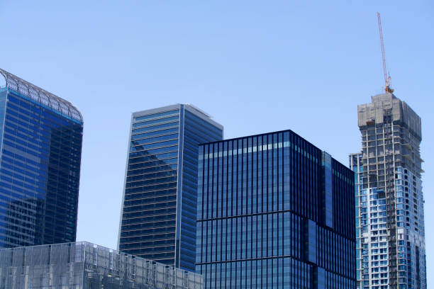 A vibrant urban scene showcasing modern skyscrapers with a clear blue sky. The image captures construction activity, emphasizing innovation and growth in the city.