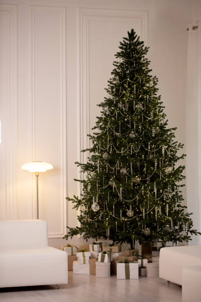 istock A large Christmas tree with lights and ornaments sits in a room with white walls 2185515566