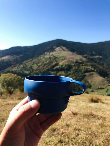 istock Hand holding blue cup with scenic mountain view in background 2185516856