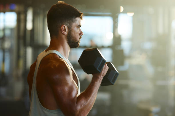 istock Determined athletic man exercising with dumbbells in a gym. 2185518057