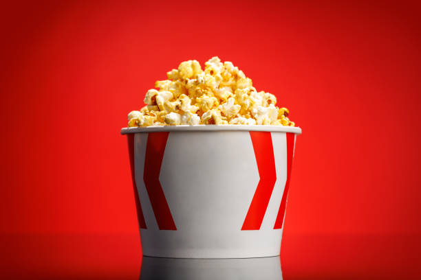 istock A box of fluffy popcorn against a vibrant red background 2185519693