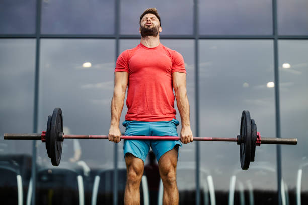 istock Powerful strong bodybuilder lifting barbell at gym during his strength training. 2185526073