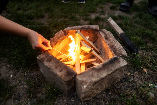 Cropped picture of an unrecognizable person firing campfire in backyard.