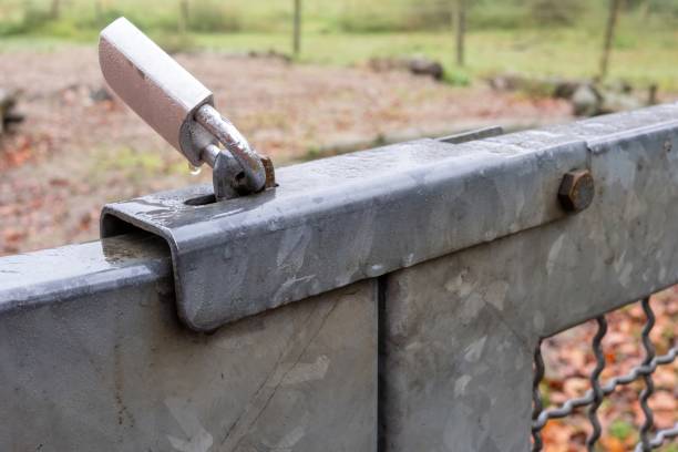 istock Secure metal gate closed with padlock in wet rural area 2185526986