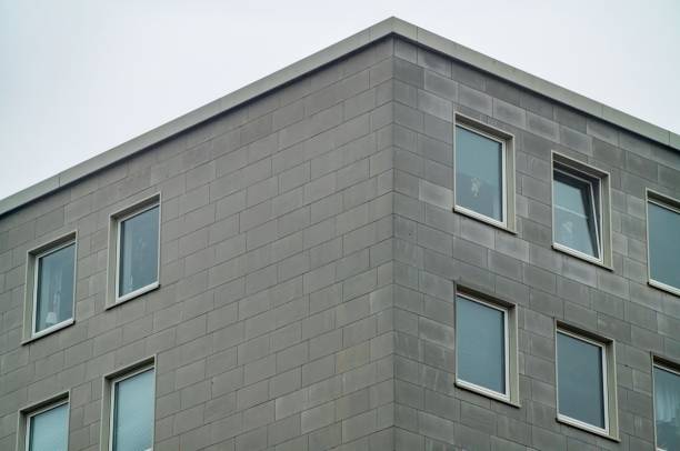 istock Modern building exterior showing gray concrete blocks and windows reflecting overcast sky 2185527432