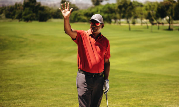 istock Golfer greeting with raised hand while resting during a match at the golf club. 2185528846