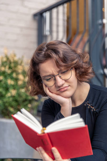istock A stressed young woman is reading a book. Emotions concept. 2185529103