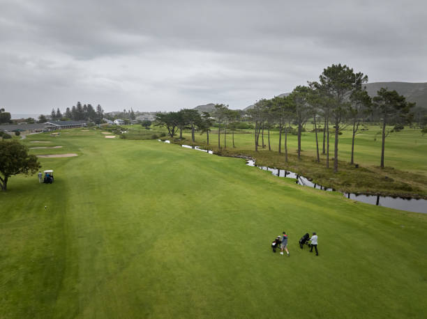 Golfers walking on green fairway on overcast day at golf course