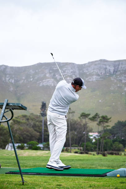 istock Golfer taking a swing on the driving range with mountains in background 2185529955