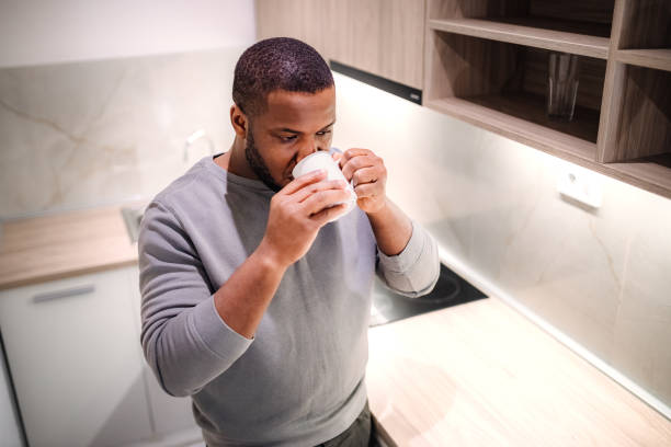 istock Young black man drinking hot cup of coffee in the kitchen 2185530836