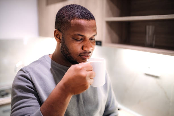 istock Young black man drinking hot cup of coffee in the kitchen 2185530894