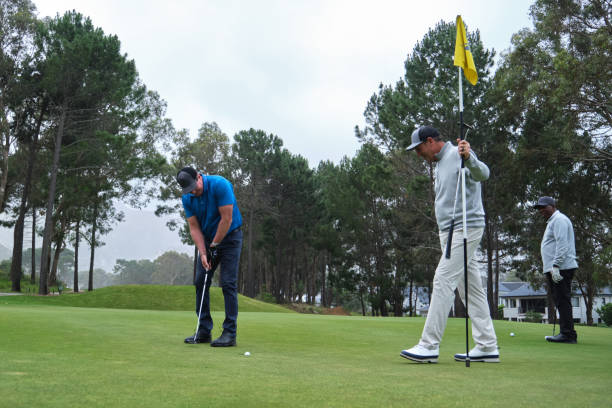 Legs of amateur golfer putting ball from the green during summer day