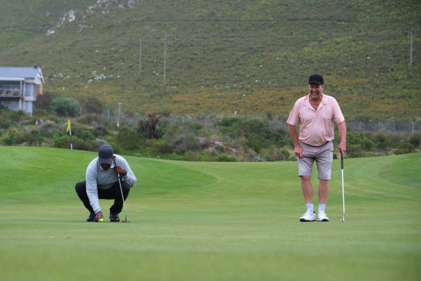 istock Golfers putting on green with mountain view 2185531732