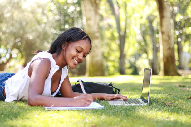 istock Black female student lying on grass with a notebook and laptop 2185531880