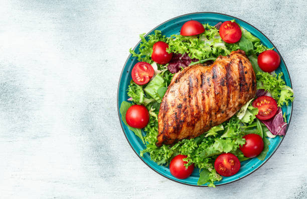 istock Grilled chicken breast ( fillet ) with lattuce salad and cherry tomatoes . Top view 2185535820