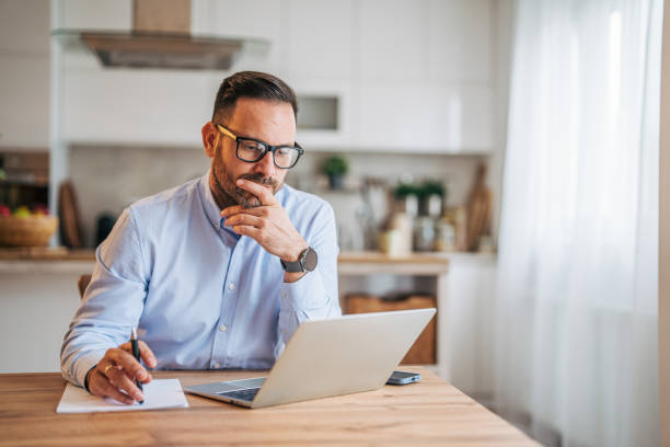 istock A 36-year-old cheerful, handsome businessman sitting in the kitchen and using a laptop. 2185536317
