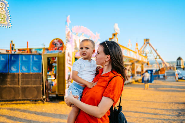 istock Young Mother Holding Her Son In An Amusement Park 2185537835