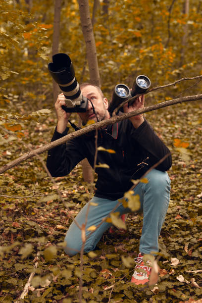 istock Man using binoculars and camera for birdwatching and other observing animals in nature. 2185538575