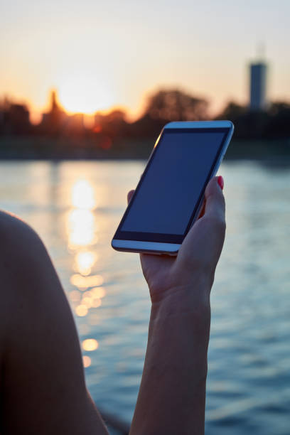 istock Woman holding cellphone outdoors in sunset time. 2185538777