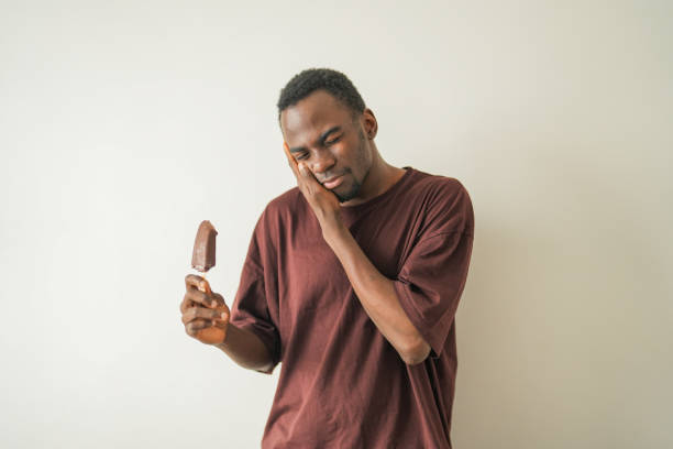 istock Young black man with tooth sensitivity has toothache after biting ice cream. 2185540100