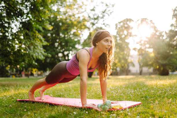 istock Young woman trainer in tracksuit changes yoga pose at public park. 2185540525