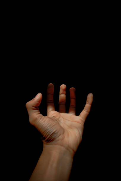 istock Male hand reaching for light in darkness on isolated black background. Selective focus on hand 2185545448