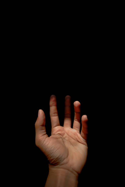 istock Male hand reaching for light in darkness on isolated black background. Selective focus on hand 2185545457