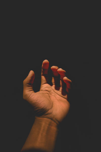 istock Male hand reaching for light in darkness on isolated black background. Selective focus on hand 2185545470