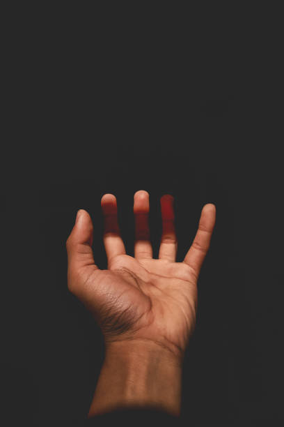 istock Male hand reaching for light in darkness on isolated black background. Selective focus on hand 2185545485