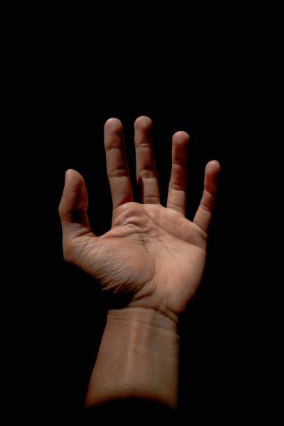 istock Male hand reaching for light in darkness on isolated black background. Selective focus on hand 2185545495