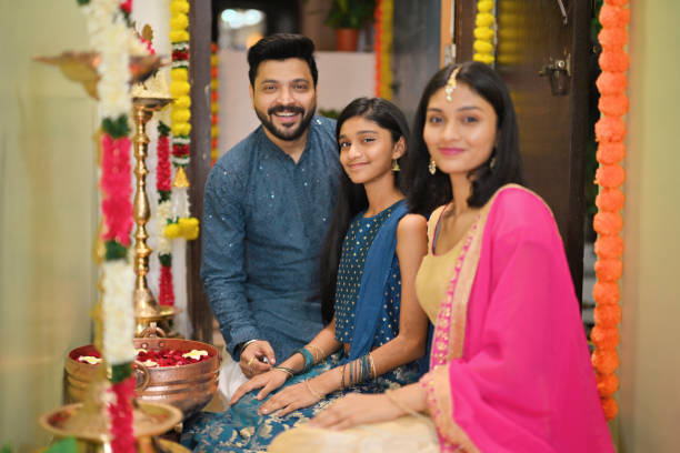 istock Father and his two daughters looking at the camera while decorating a lamp (diya) in an Urli during Diwali celebration 2185546051