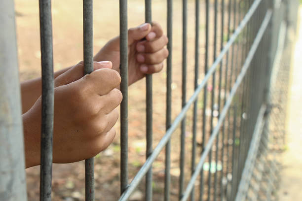 istock hand holding an iron fence or prison 2185547332